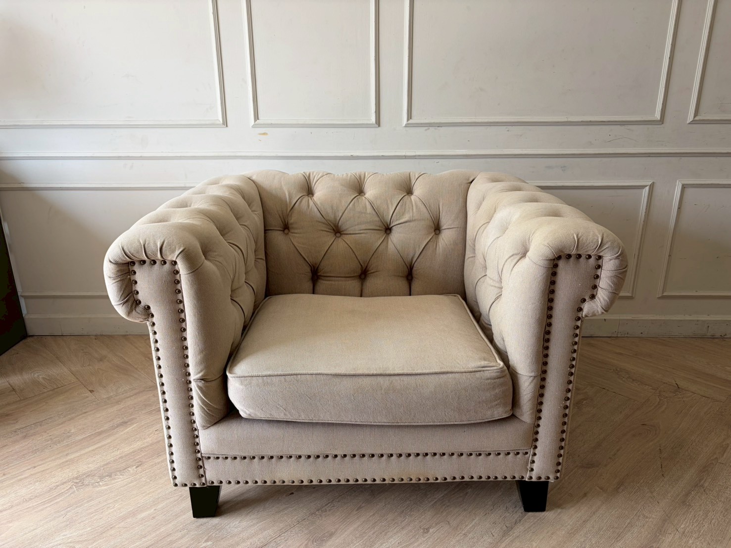Chesterfield style armchair with cream-colored fabric and button tufting. (1)