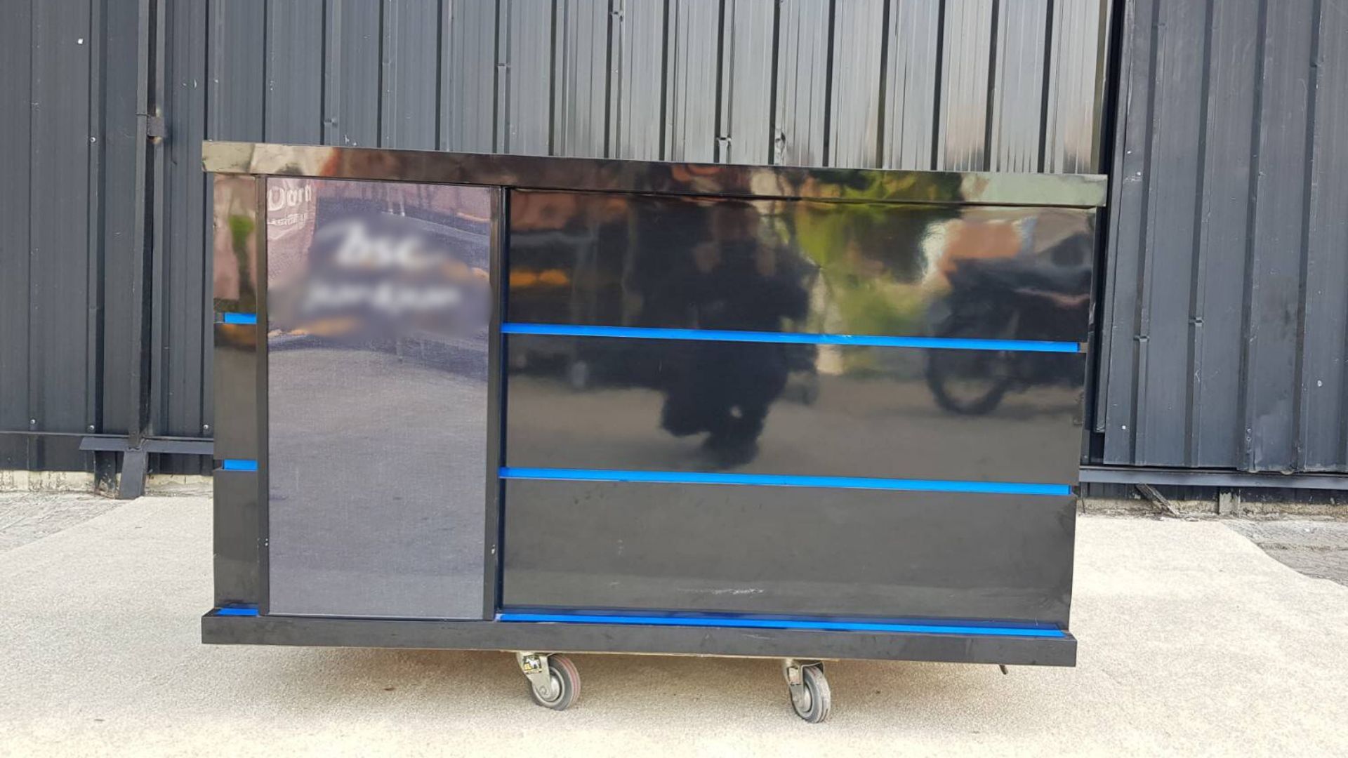 Black wooden counter with 2 sliding doors and 4 drawers.