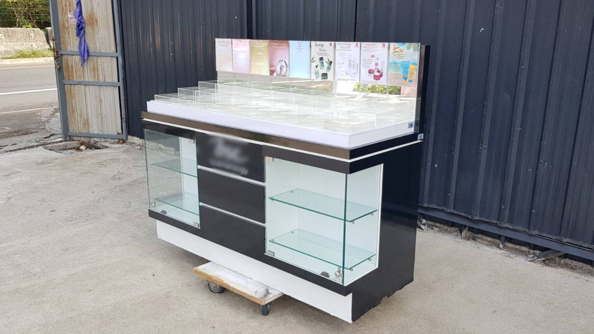 玻璃展示柜，黑色木质化妆品展示柜，配有两扇玻璃门和三扇木门。