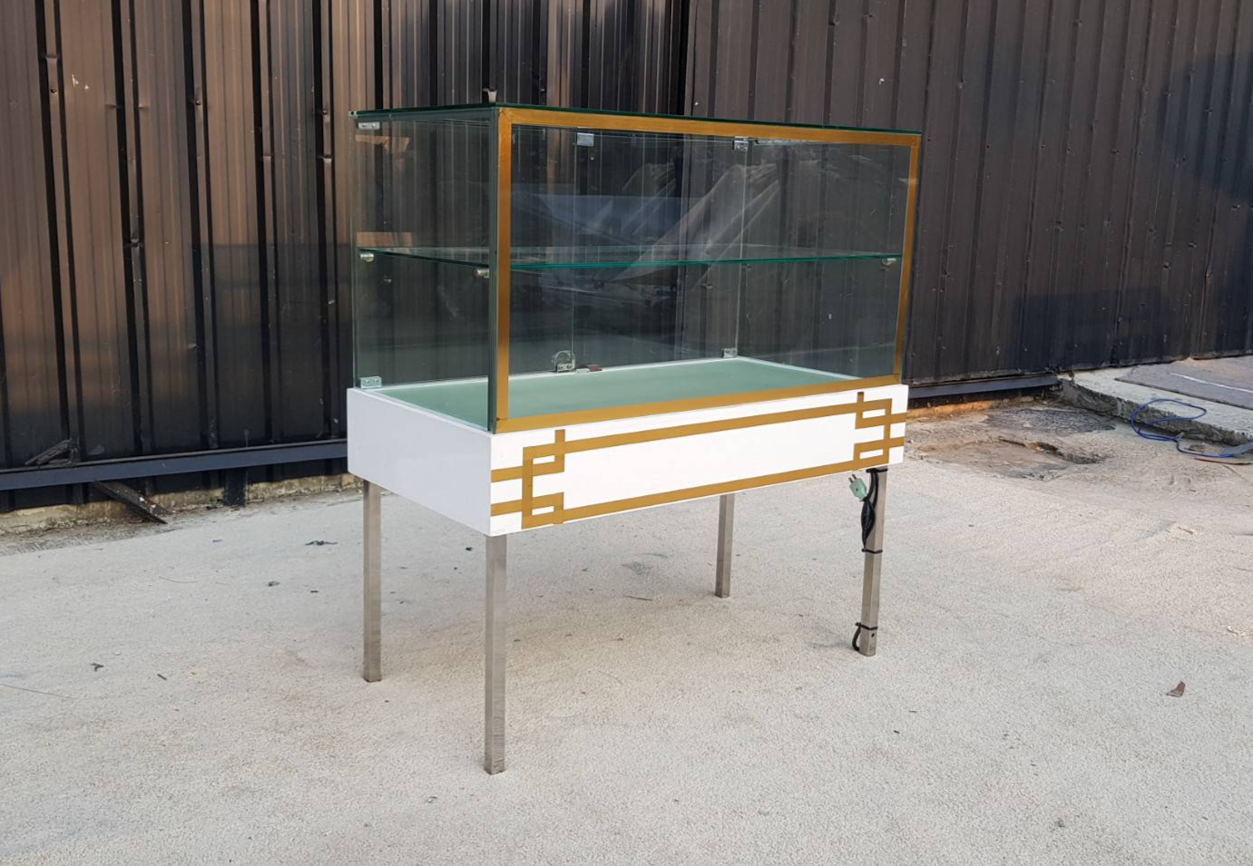 White glass display case with two doors and steel legs.