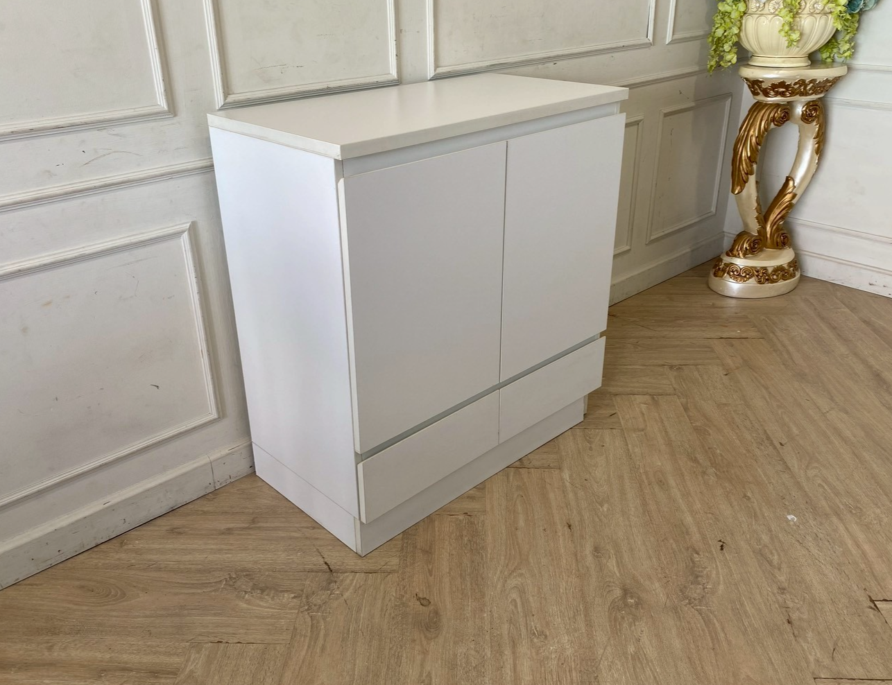White wooden shoe cabinet with two doors and two drawers.