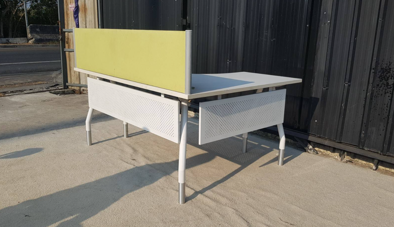 L型转角办公桌，白色钢制桌腿，浅黄色隔板。宽160厘米。