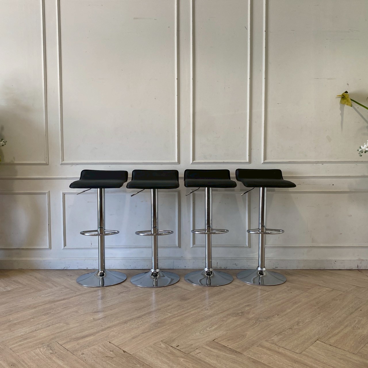 Bar stool with steel legs and black leather seat.