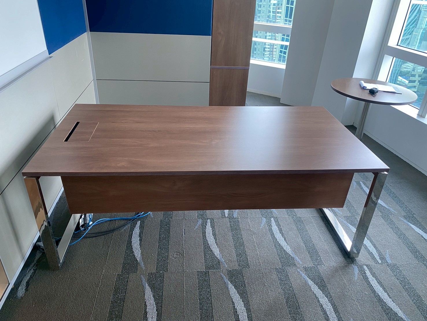 行政办公桌，钢制桌腿，棕色木质桌面，配有电源插座。