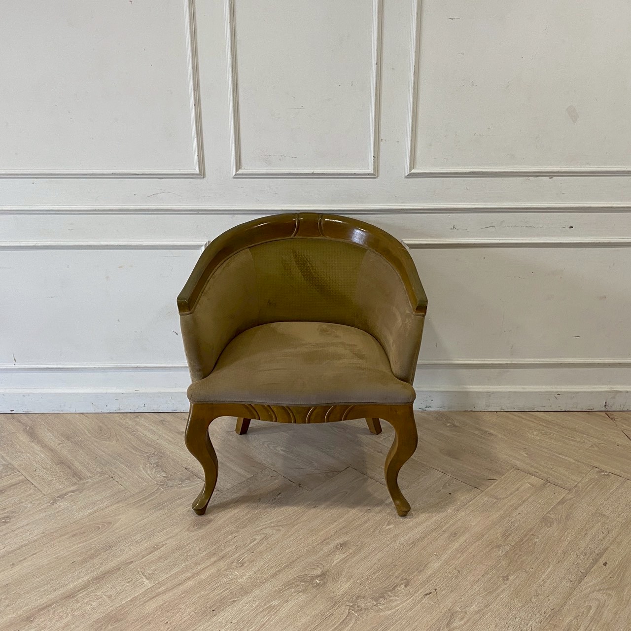 Brown armchair with velvet upholstery and wooden legs.