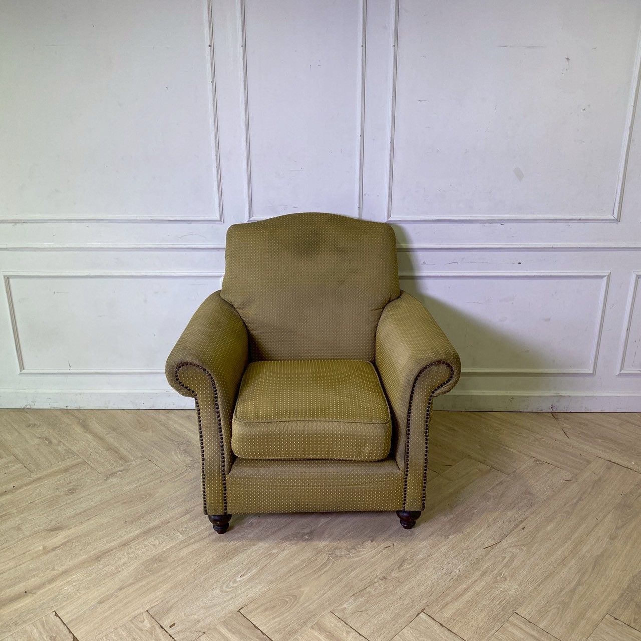 Armchair with wooden legs and brown fabric seat with yellow polka dots.